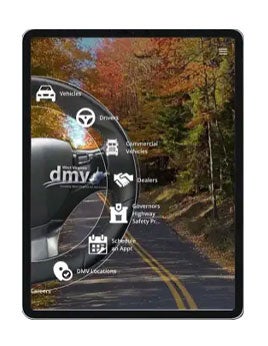 A tablet screen displaying the West Virginia DMV digital homepage, featuring an overlay of service navigation icons around a steering wheel set against a background of a scenic mountain road in autumn